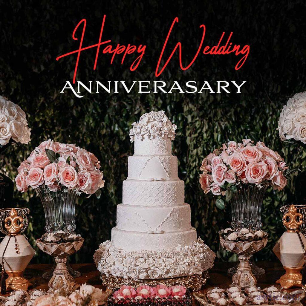 A big, three-tiered anniversary cake surrounded by a vase of red and pink roses.